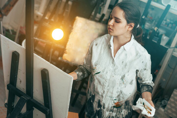 Young artist paints a picture with oil paints in a creative workshop on canvas