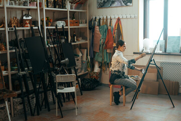 Young artist paints a picture with oil paints in a creative workshop on canvas