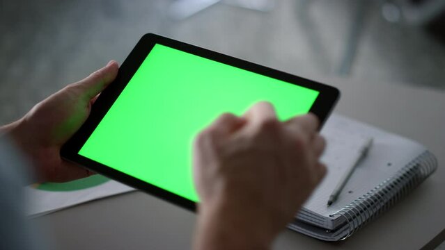 Businessman swiping tablet pad green screen analyzing corporate data in office.