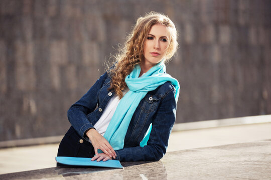 Young fashion blonde woman in denim jacket and light blue scarf