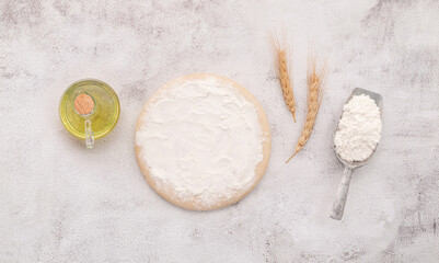 Wheat grains , brown wheat fThe ingredients for homemade pizza dough with wheat ears ,wheat flour and wheat grains set up on white concrete background.
