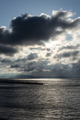 Fototapeta premium 雲の合間から薄明光線、海岸線と大型船