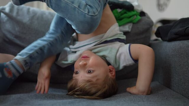 little boy upside down on sofa at home playful child at home playing