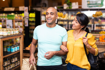 Casual latin american family couple doing shopping together in food department of supermarket