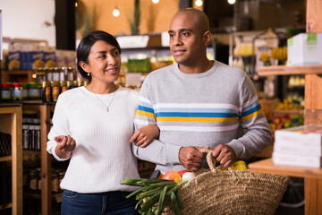 Family couple with bag of groceries with grocery store