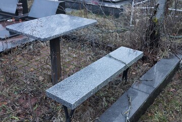 gray bench and table of stone and marble at the grave in the cemetery