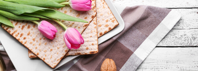 Jewish flatbread matza for Passover Seder and tulip flowers on wooden background