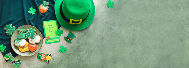 Tasty gingerbread cookies for St. Patrick's Day celebration and leprechaun hat on grunge background with space for text