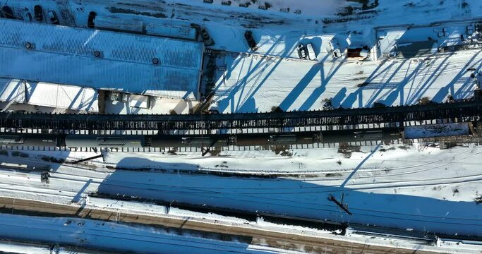 Top down aerial of cargo train on railroad track in winter snow. Transportation freight theme. Bright sunny daytime shot.
