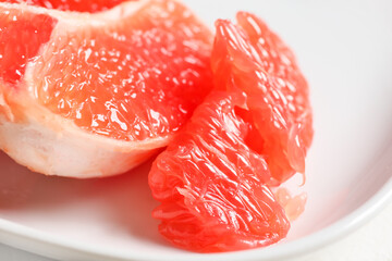 Plate with tasty grapefruit pieces on light background, closeup