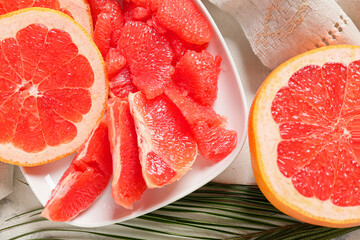 Plate with tasty grapefruit pieces on light background