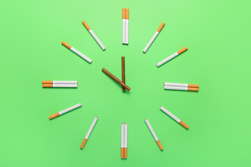 Clock made of cigarettes on green background