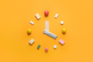 Clock made of different chewing gums on color background