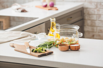 Cooking pot with healthy vegetables on table in kitchen