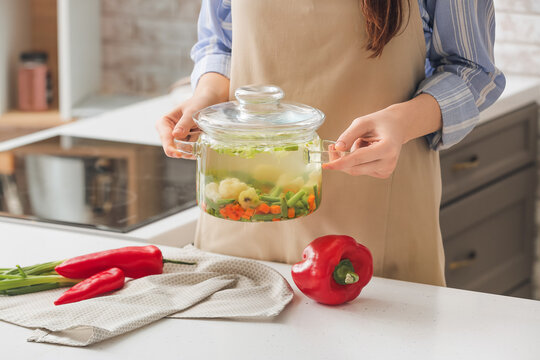 Woman With Cooking Pot Of Tasty Dietary Soup On Table In Kitchen