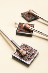 Makeup brush and eye shadow palette on light background
