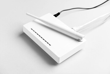 Wi-Fi router with antenna and network cables on light background