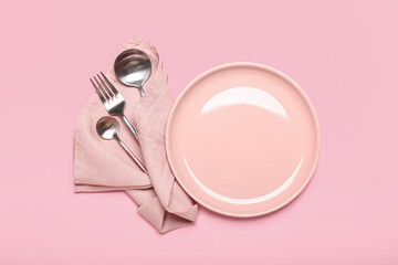 Plate and set of cutlery on color background
