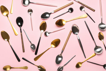 Different stainless steel spoons on color background