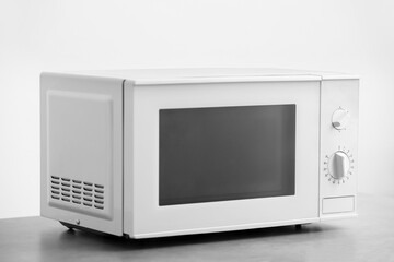 Fototapeta premium Modern microwave oven on table against light background