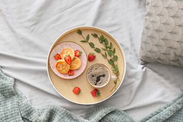 Fototapeta na wymiar Tray with tasty breakfast and eucalyptus branch on bed