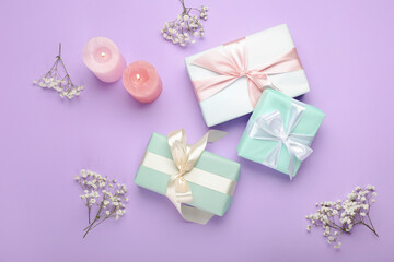 Gift boxes, burning candles and gypsophila flowers on color background