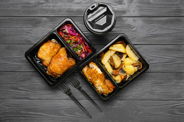 Lunch boxes with delicious food, paper cup and forks on grey wooden background