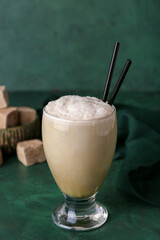 Glass of iced hojicha latte on green background