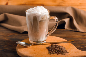 Glass of tasty iced hojicha latte and powder on wooden table, closeup