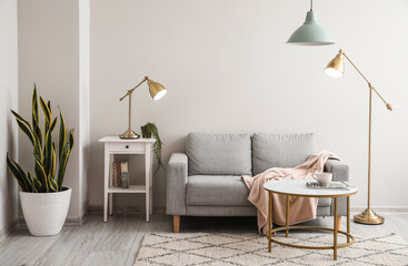 Interior of light living room with grey sofa, table and lamps - Powered by Adobe