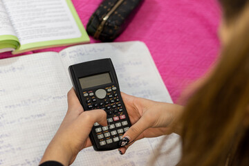 Close up of teenager girl hands counting by calculatior at home