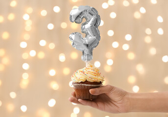 Woman holding Birthday cupcake against blurred background