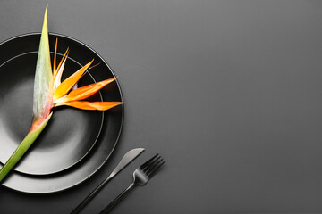 Simple table setting with bird of paradise flower on dark background