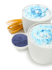 Obraz na płótnie Canvas Cups of blue matcha latte, powder and chasen on white background, closeup