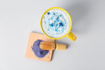 Cup of tasty blue matcha latte with chasen and powder on white background