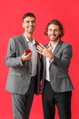 Happy engaged gay couple on red background