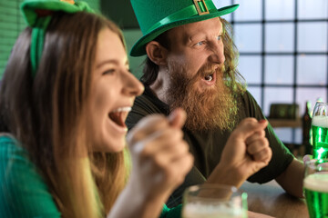 Emotional bearded man watching football game in pub on St. Patrick's Day - obrazy, fototapety, plakaty