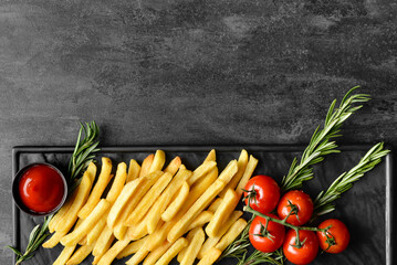 Naklejka na ściany i meble Board with tasty french fries and fresh tomatoes on black background