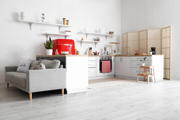Interior of light kitchen with white counters and sofa