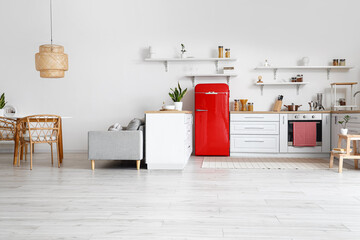 Interior of light kitchen with white counters and red fridge
