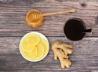 The best cold remedy, hot tea, lemon, honey and ginger root on a wooden table.