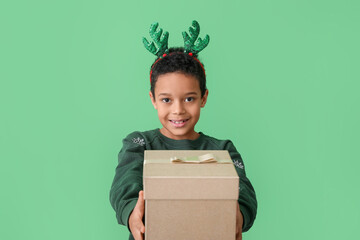 Cute little African-American boy with Christmas box on color background © Pixel-Shot