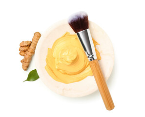 Bowl with turmeric mask and makeup brush on white background