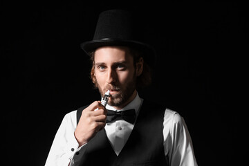 Vaping young man on black background