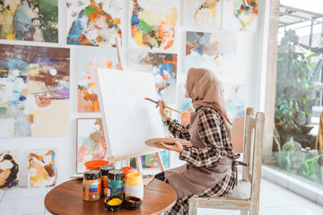 asian muslim female artist start painting on blank canvas