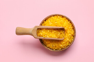 Bowl with orange sea salt and scoop on pink background