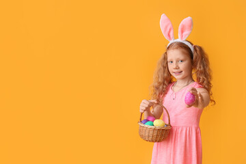 Obraz na płótnie Canvas Funny little girl with bunny ears and Easter basket on color background