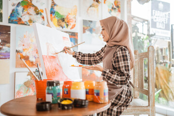 Fototapeta na wymiar muslim asian female artist painting on canvas