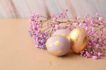 Beautiful Easter eggs and gypsophila flowers on table, closeup