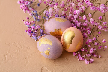 Beautiful Easter eggs and gypsophila flowers on color background, closeup